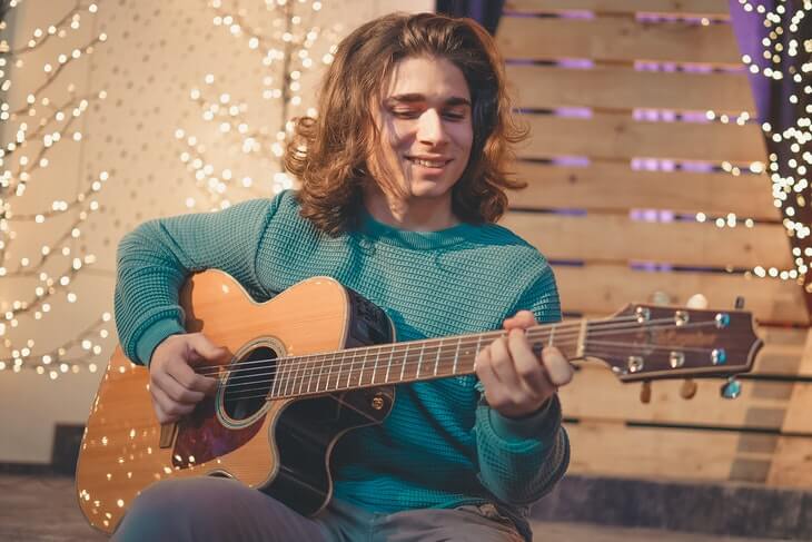 Man Sitting While Playing Guitar