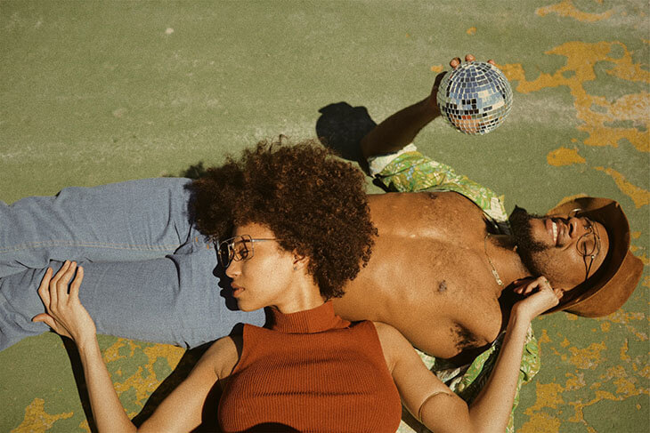 Woman in brown turtleneck sleeveless top lying on man