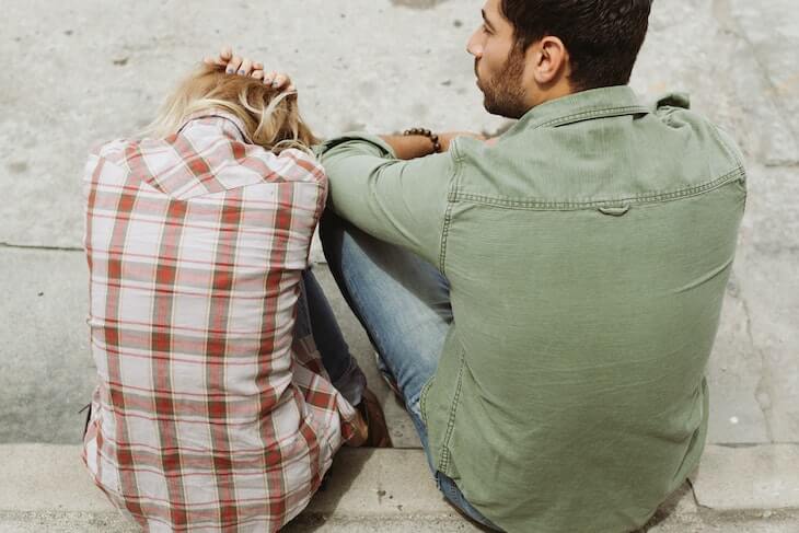 Man and Woman Sitting on Sidewalk