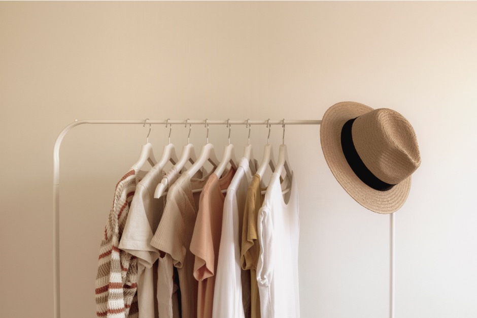 Some clothes and hats hanging on the hangers.