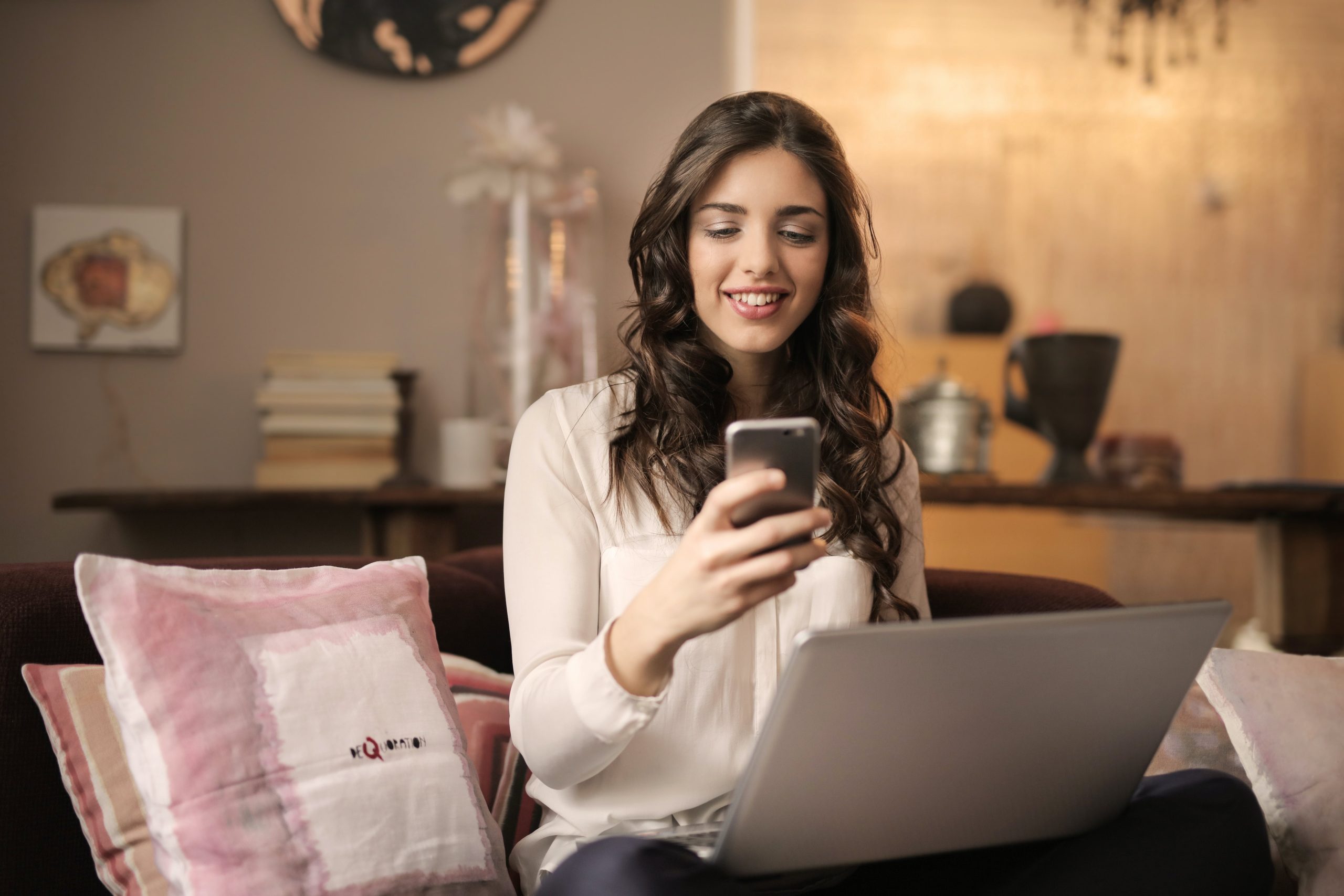 A happy woman sitting on the sofa ， taking conversation with someone on her mobile phone.