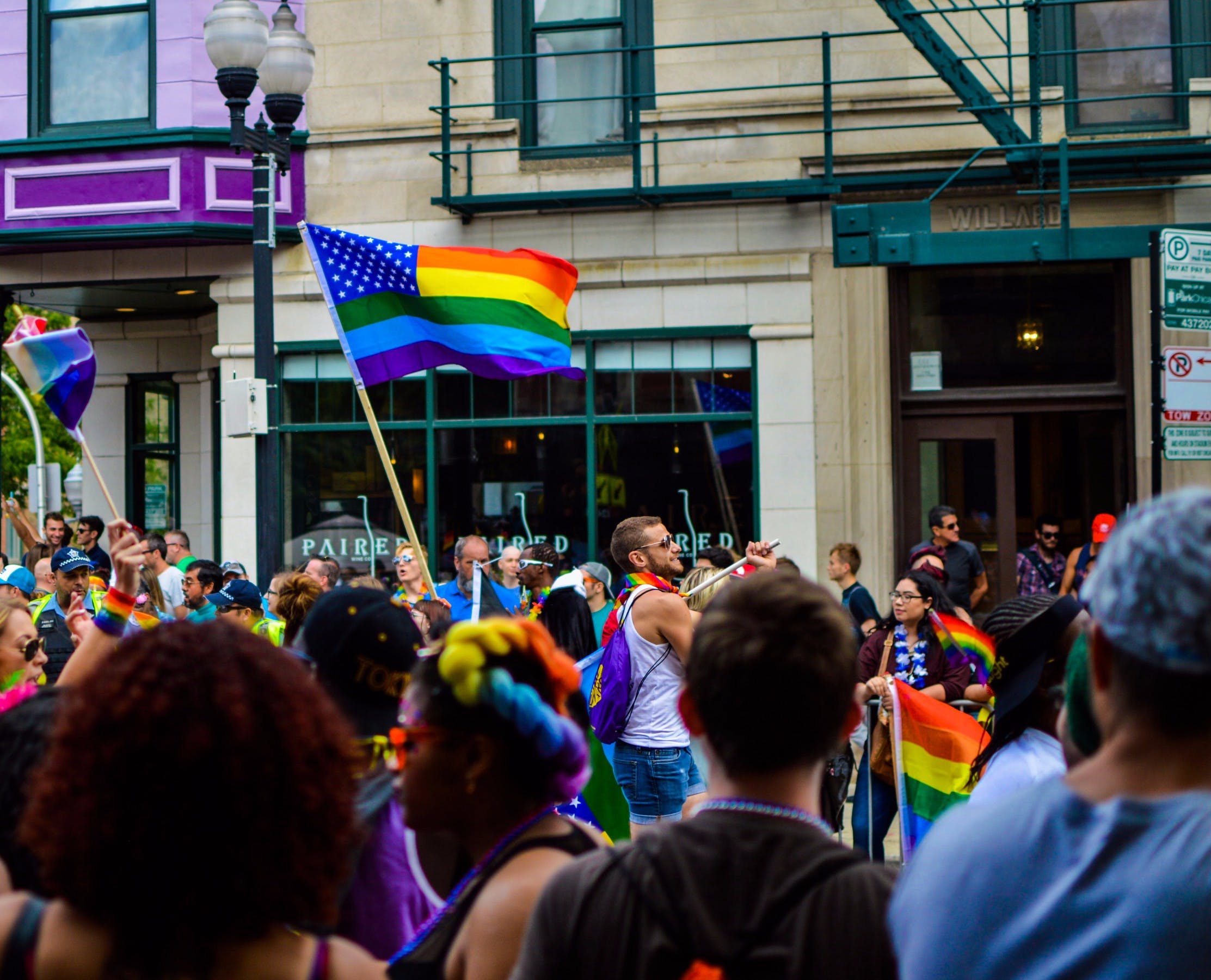 A group of people holding rainbow flags are marching in the street