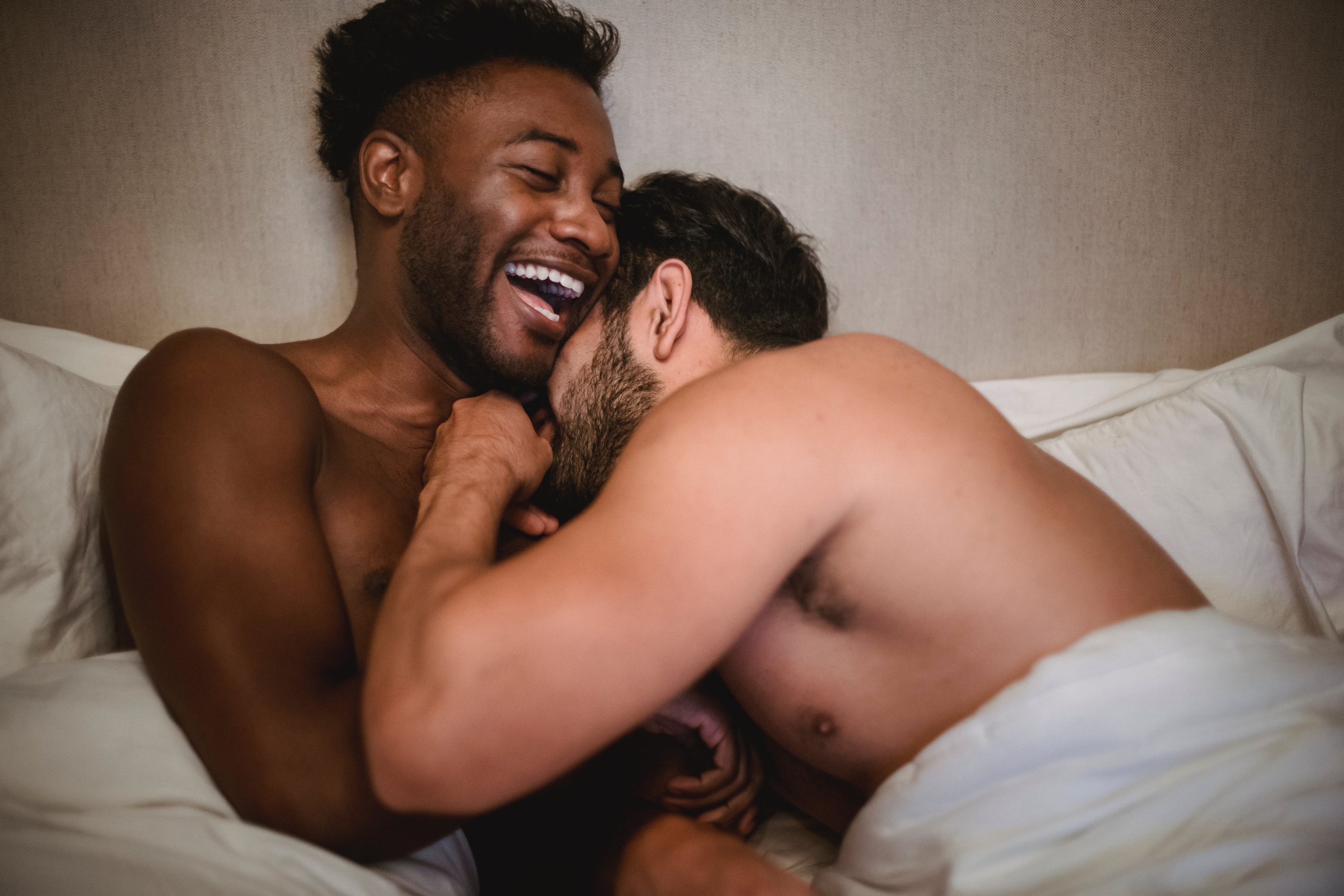 2 LGBTQ lovers laughing in bed