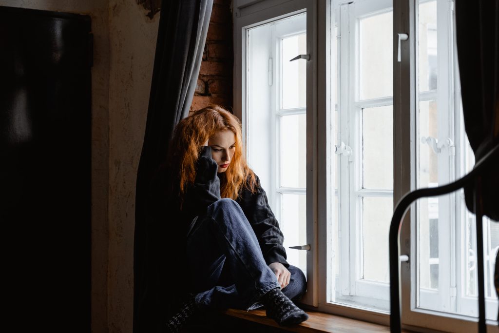 A girl sitting on the windowsill, lost in contemplation, with a restless mood.