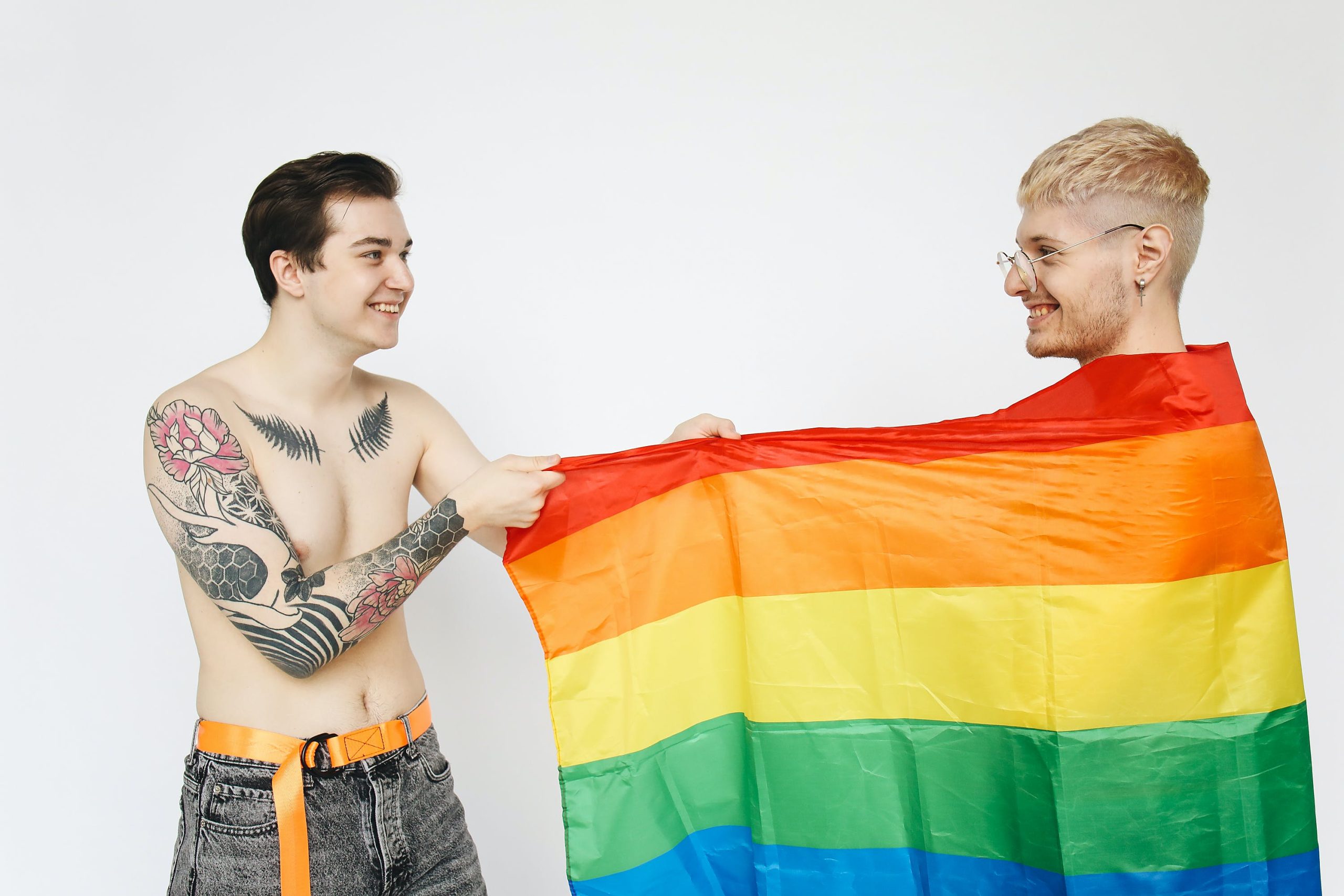 A pair of male lovers having fun wearing rainbow flags, 