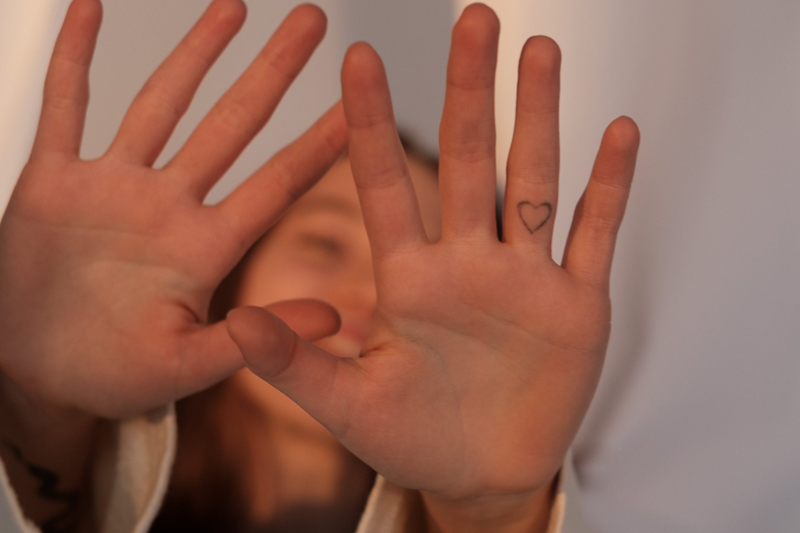 The girl smiled and stretched out her hands to cover the camera because of shyness.